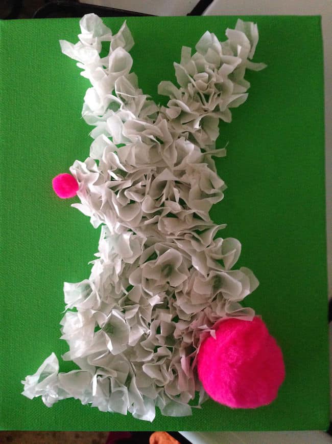 Attaching pink pom poms to the canvas bunny