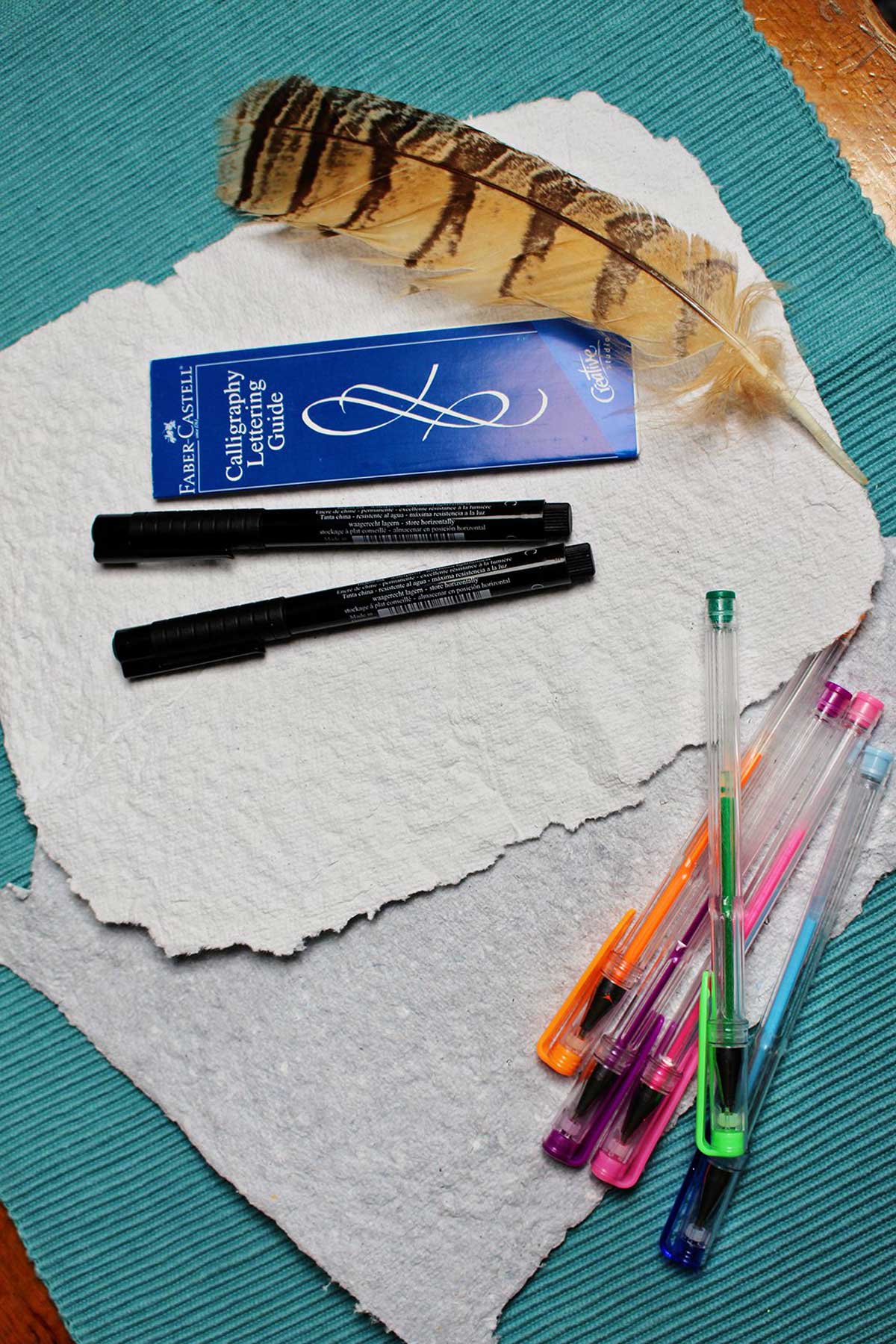 Recycled paper sheets, gel pens, markers, a quill.