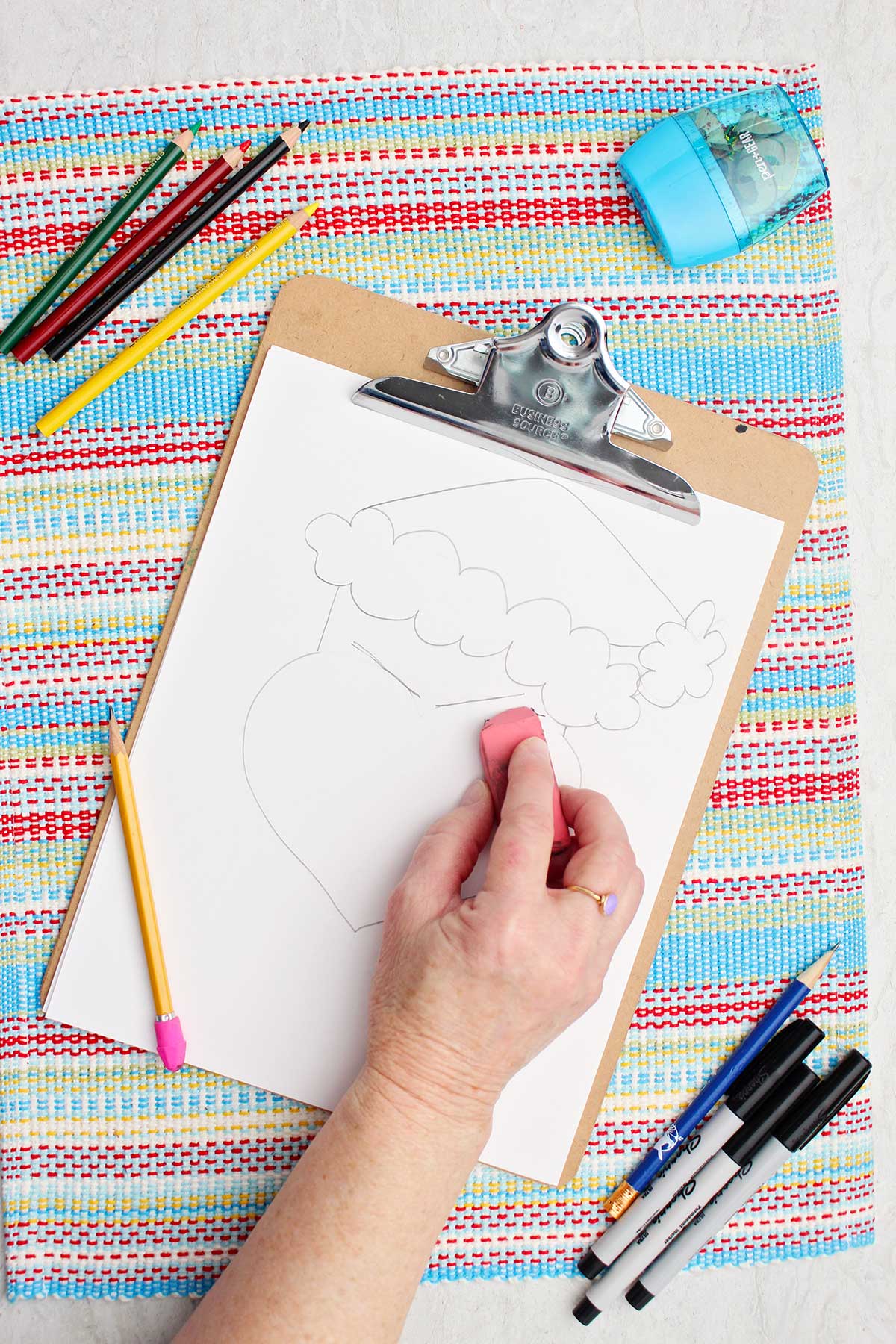 Individual erasing some lines near the eyes on their Grinch drawing.