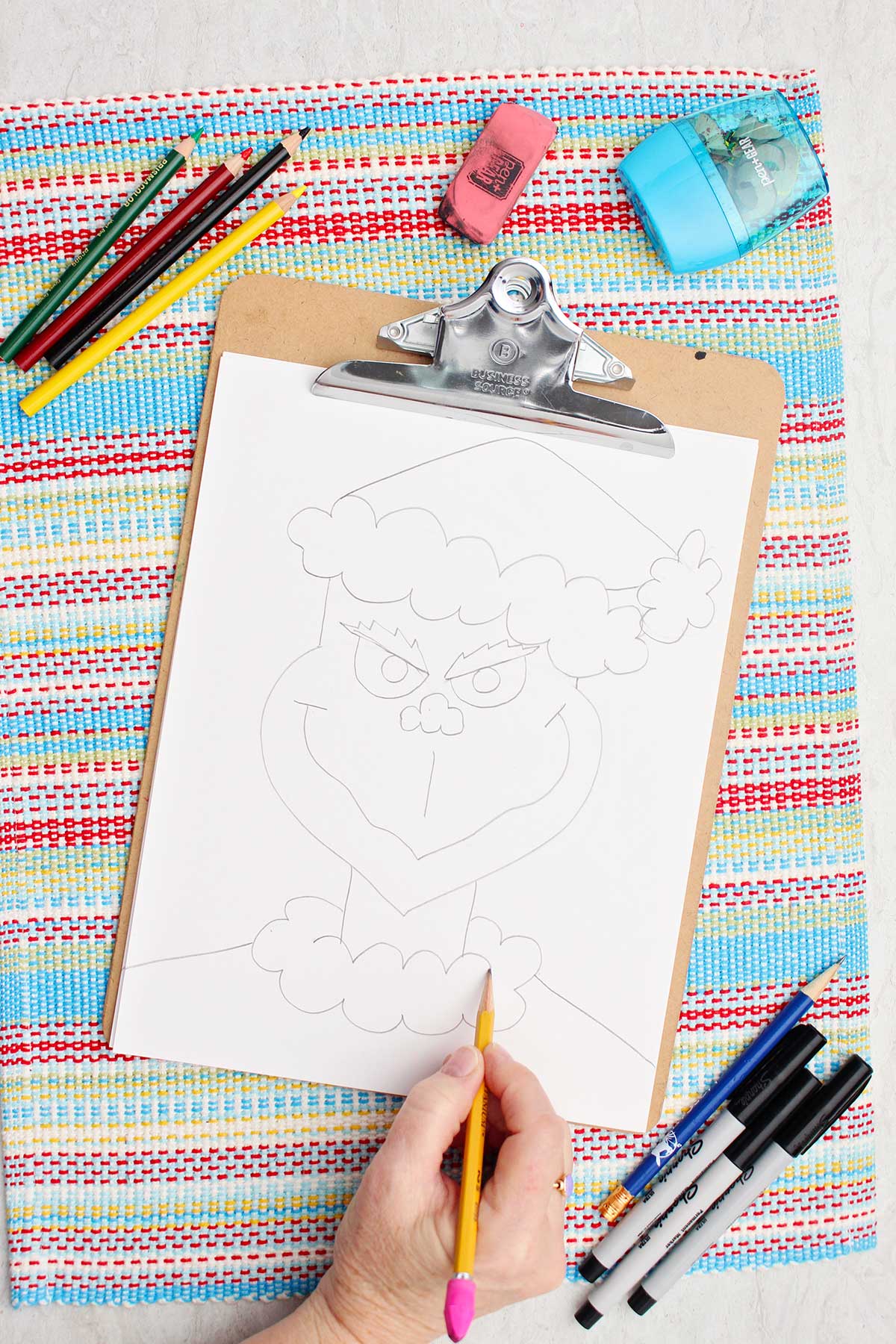 Person enhancing trim details on the Grinch's Santa coat.