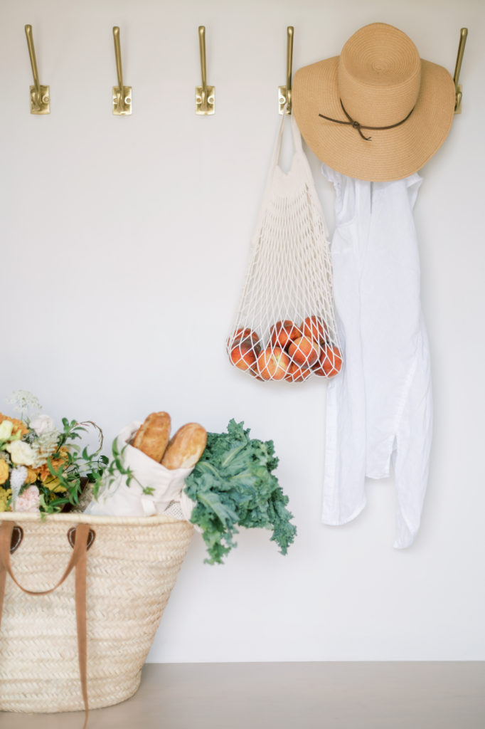 Fabric bag filled with groceries beside a sweater and hat.