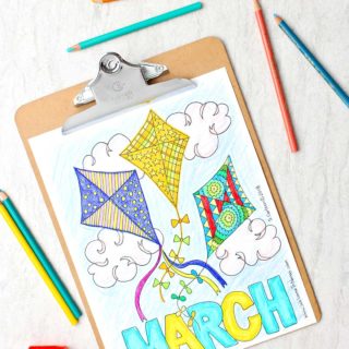 Finished March coloring sheet. Three kites with diverse patterns vibrantly filled in with colored pencils nearby.