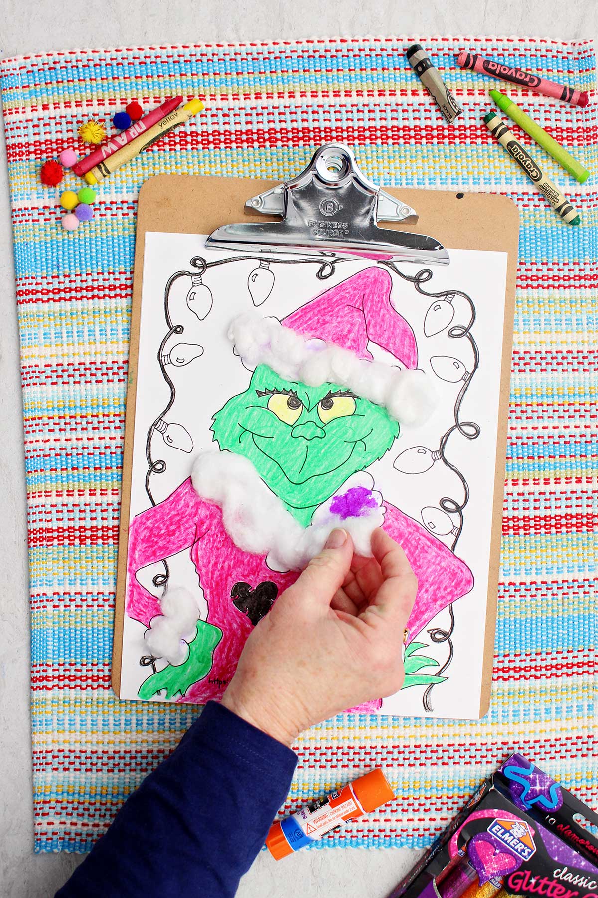 Individual attaching cotton balls onto the Grinch's Santa coat.