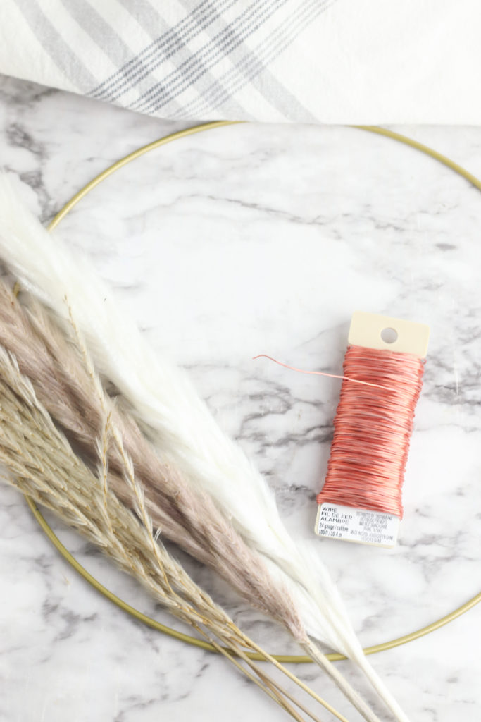 Materials required to create a pampas hoop wreath, including a metal hoop, pampas grass, and floral wire.