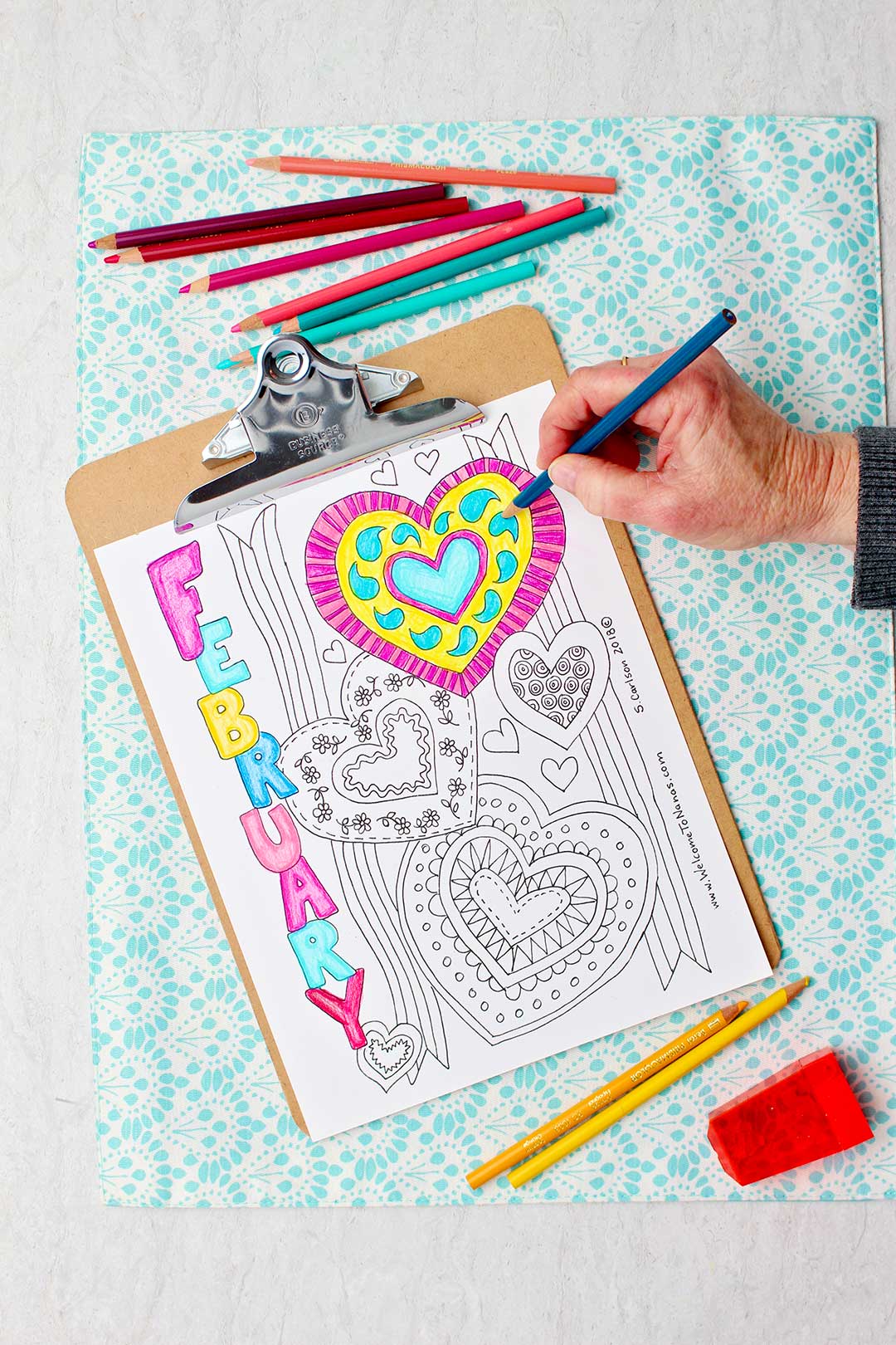 Hand coloring details inside of a blue heart on February coloring page.