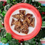 A red rimmed plate of toffee encompassed by festive ivy.
