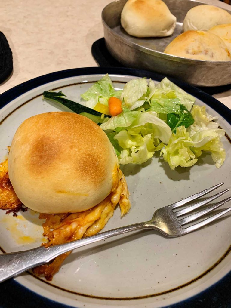 Homemade pizza pockets with cheese served on a dinner plate alongside a salad.