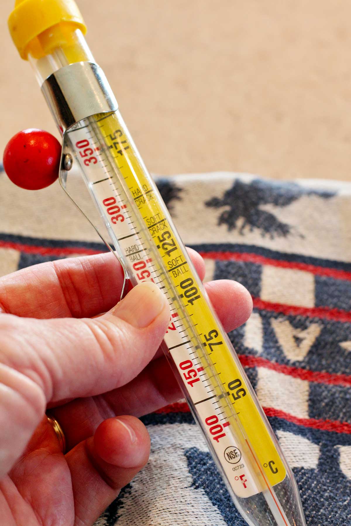 A person grasping a candy thermometer.