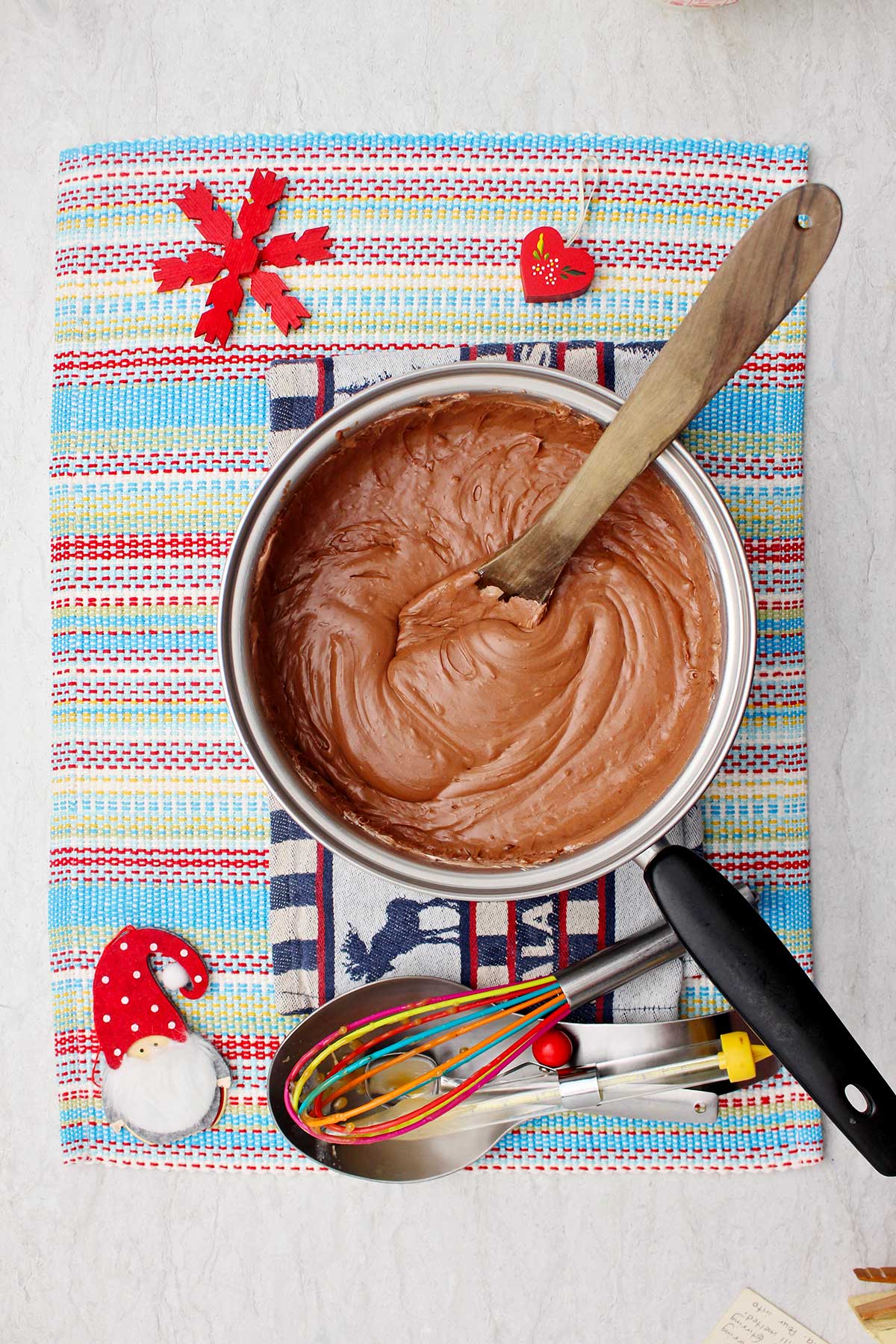 Stirred fudge mixture in saucepan on colorful placemat.
