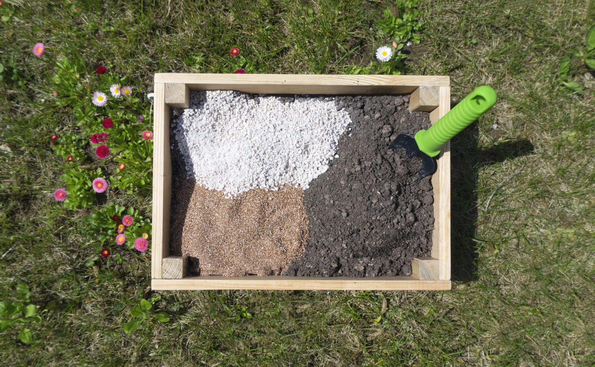 A wooden container in the garden, filled with soil and organic additives prior to mixing.