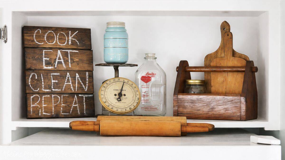 Farmhouse kitchen shelf decor featuring a wooden sign that says Cook Eat Clean Repeat, vintage scale, milk bottle, mason jar, cutting boards, and rolling pin.