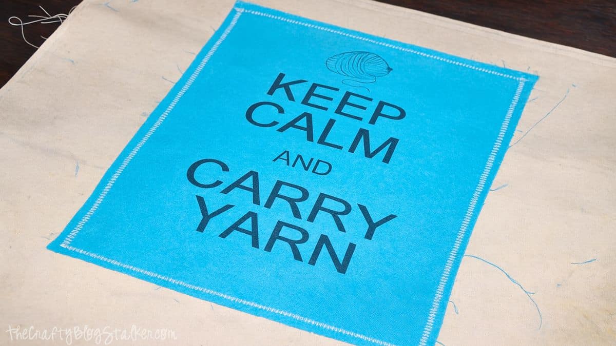 attach printable_edited-1 Blue Keep Calm and Carry Yarn fabric panel stitched onto canvas tote bag fabric during sewing project.