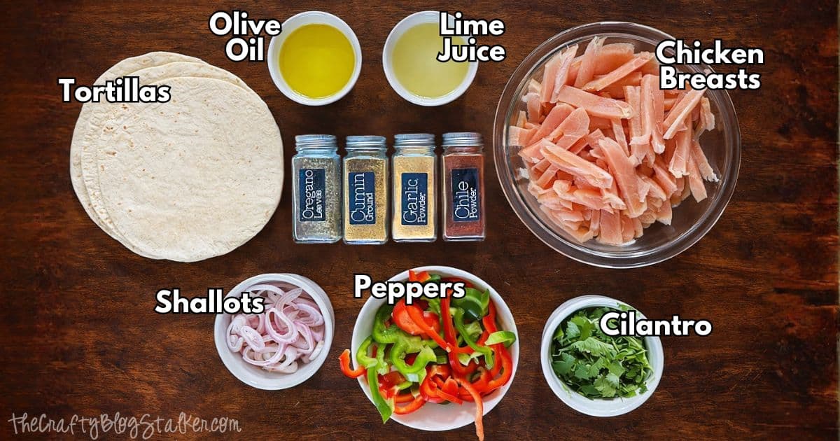Overhead perspective of baked chicken fajita components which include sliced chicken breasts, tortillas, olive oil, lime juice, peppers, shallots, cilantro, and spices.