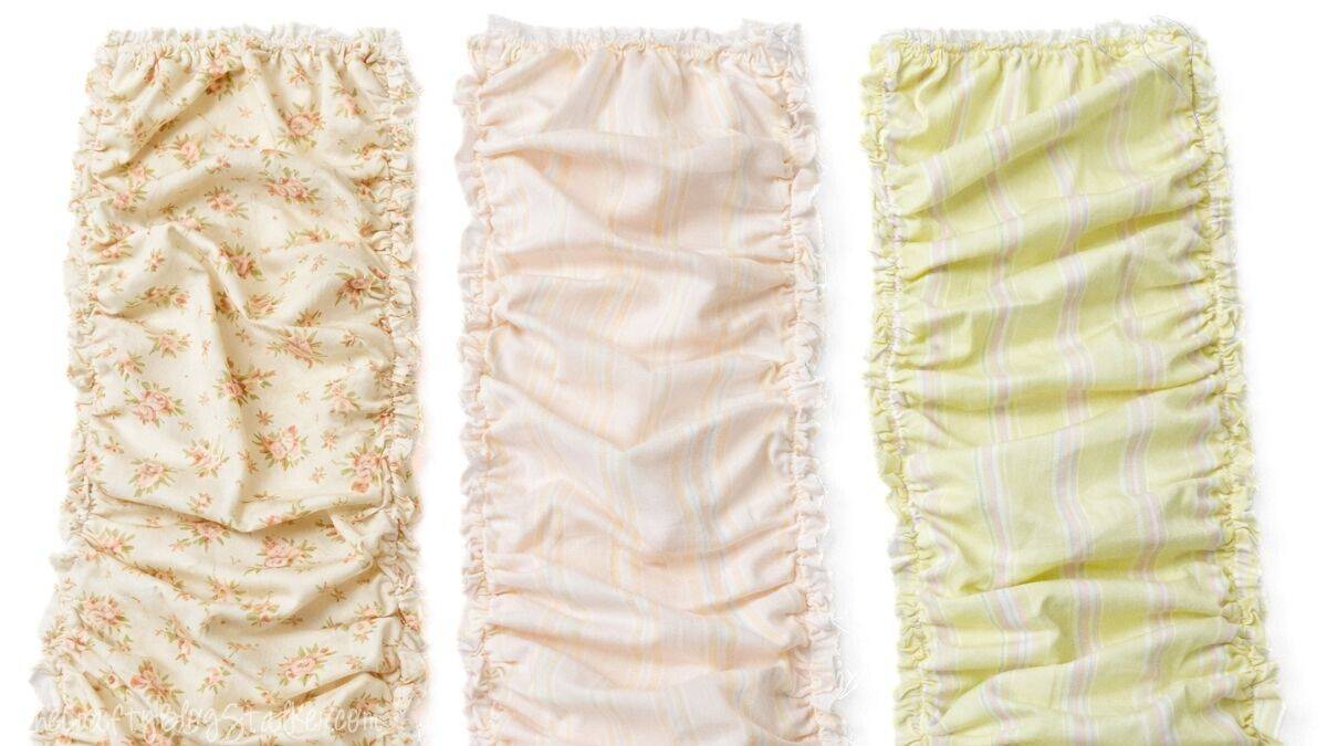 Three ruffled fabric strips arranged side by side, displaying gathered edges and various patterned fabrics ready for a doll quilt project.