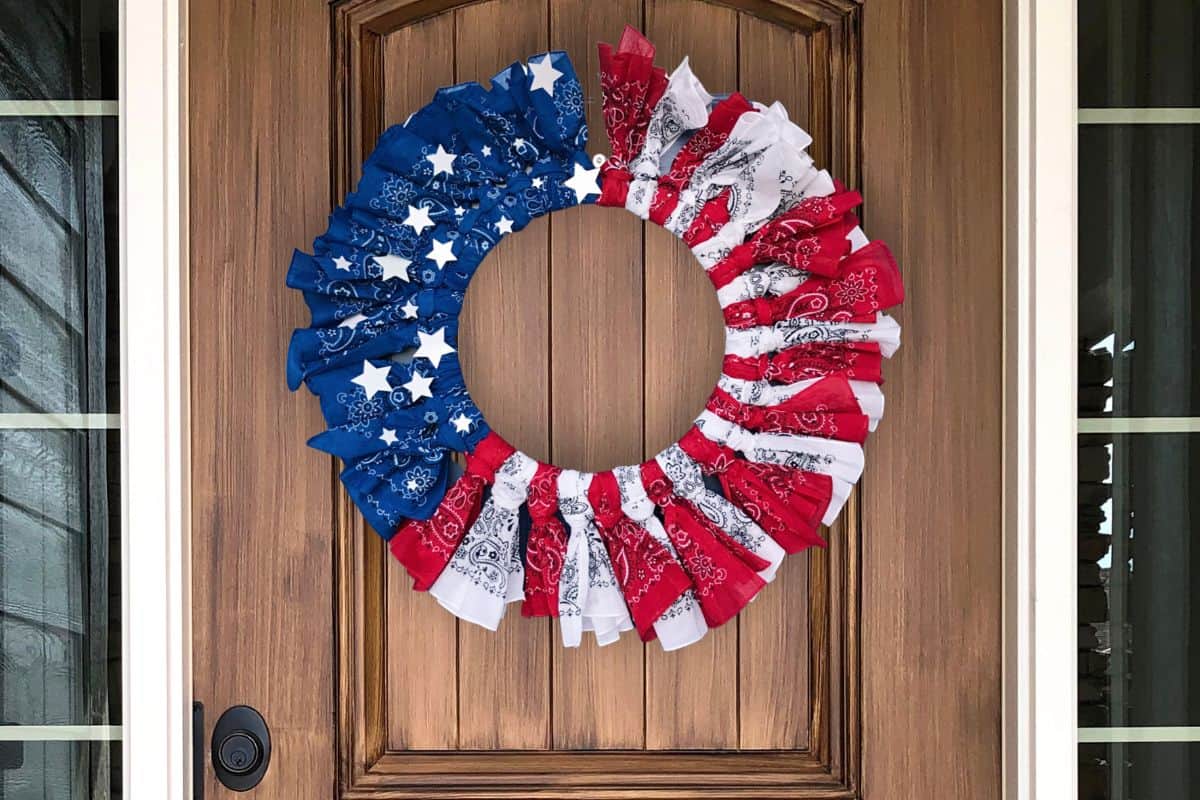 A DIY patriotic bandana wreath adorning a wooden front door.