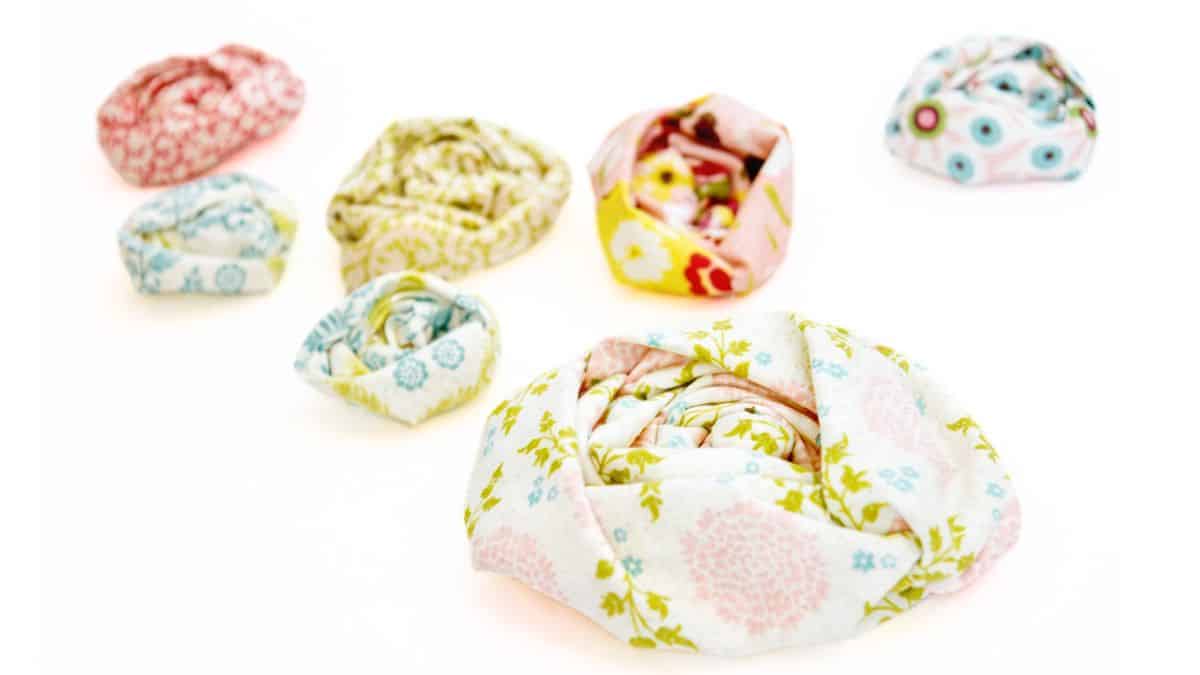Handcrafted ruched fabric flowers crafted from patterned cotton cloth, displayed in various sizes on a white surface.