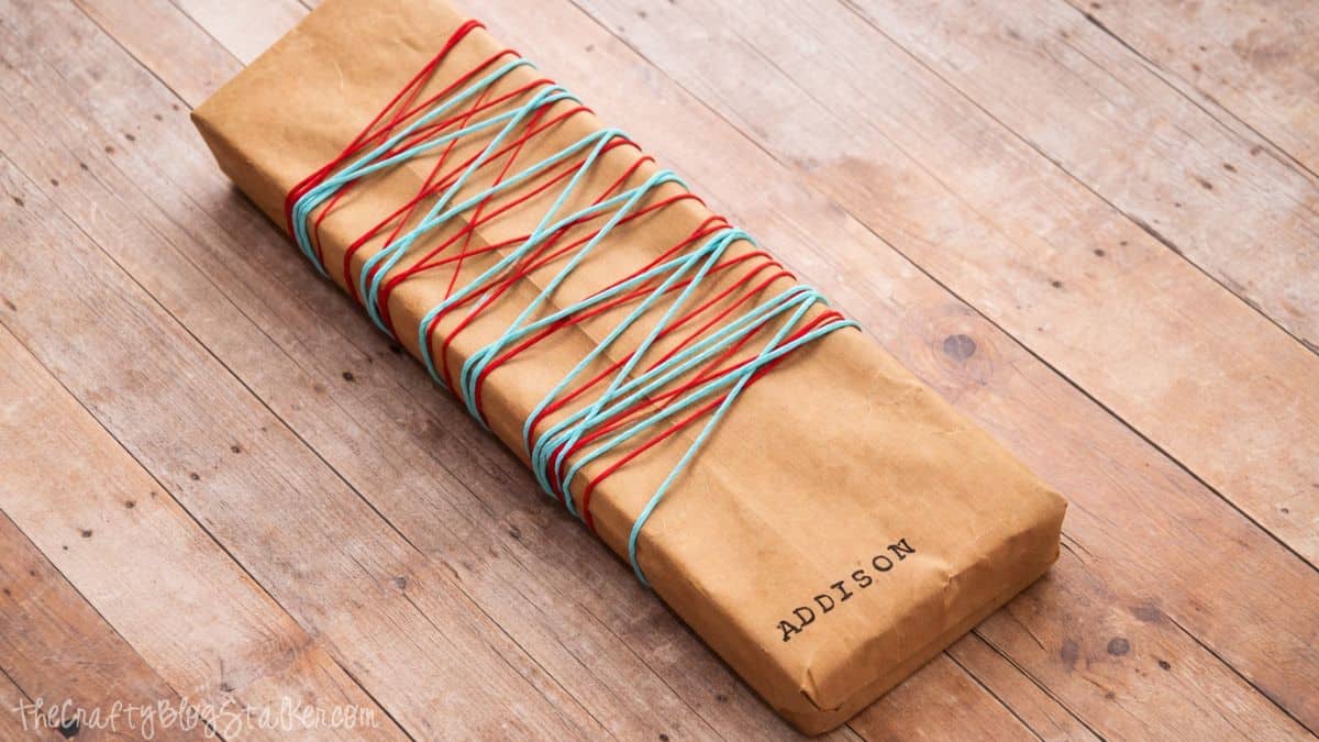 Rectangular gift perfectly wrapped in kraft paper, placed on a wooden surface, showcasing simple and minimalist present wrapping.