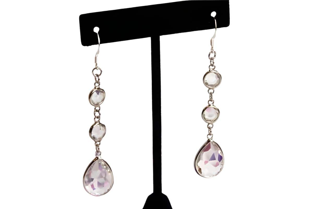 Set of handmade dangling rhinestone earrings featuring transparent faceted stones on silver hooks, displayed on a T-shaped earring stand.
