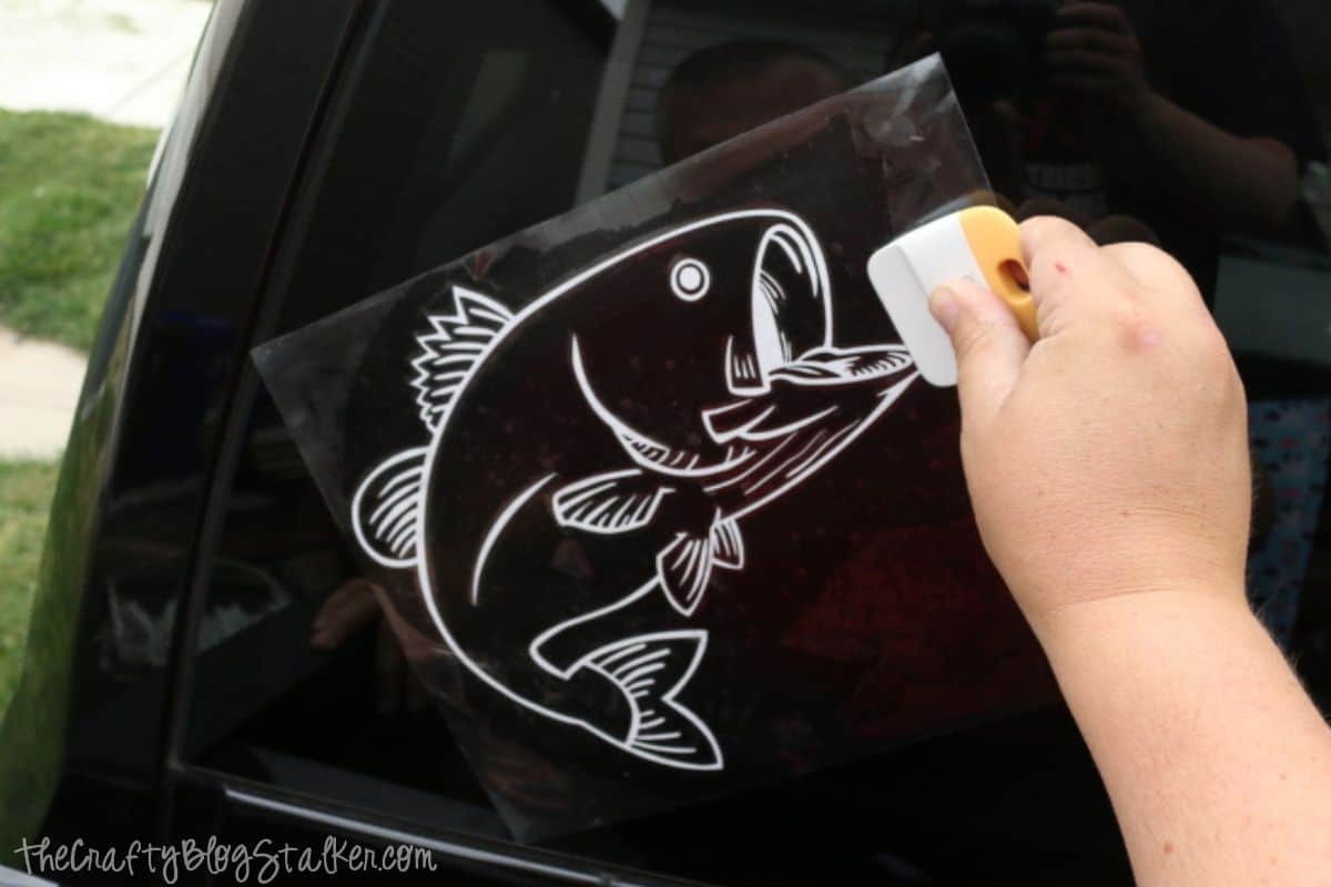 Applying a bass decal to the rear window of a truck.