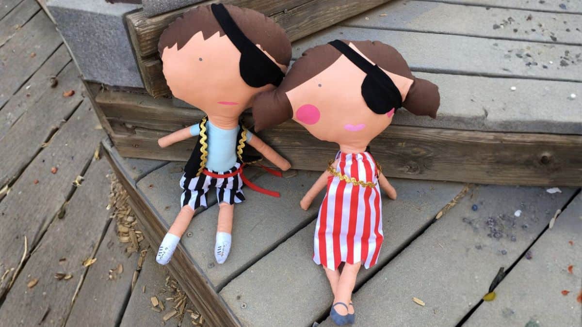 Two crafted pirate figures featuring eye patches and textile costumes positioned on outdoor wooden stairs, displayed side by side as part of a DIY creation project.