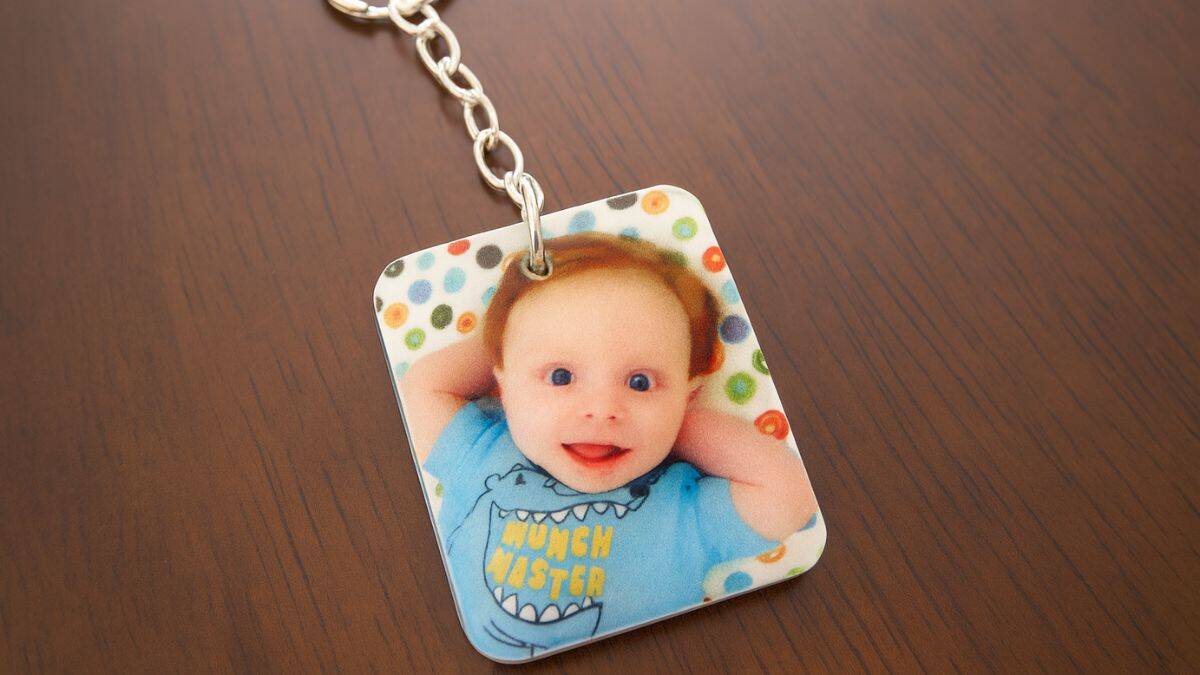 Customized photo keychain showcasing a printed image of a joyful baby on a rectangular charm attached to a metal keychain.