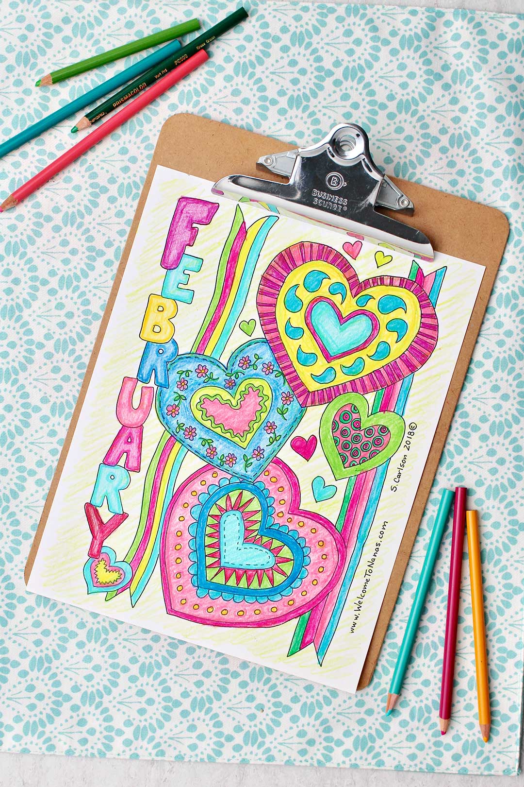 Completed February Coloring Page on a clipboard with colored pencils nearby.