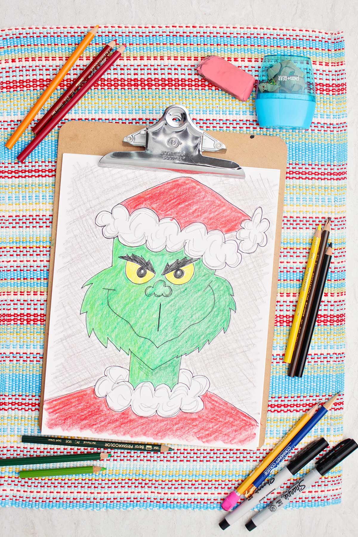 Colored version of a Grinch sketch with colored pencils nearby.