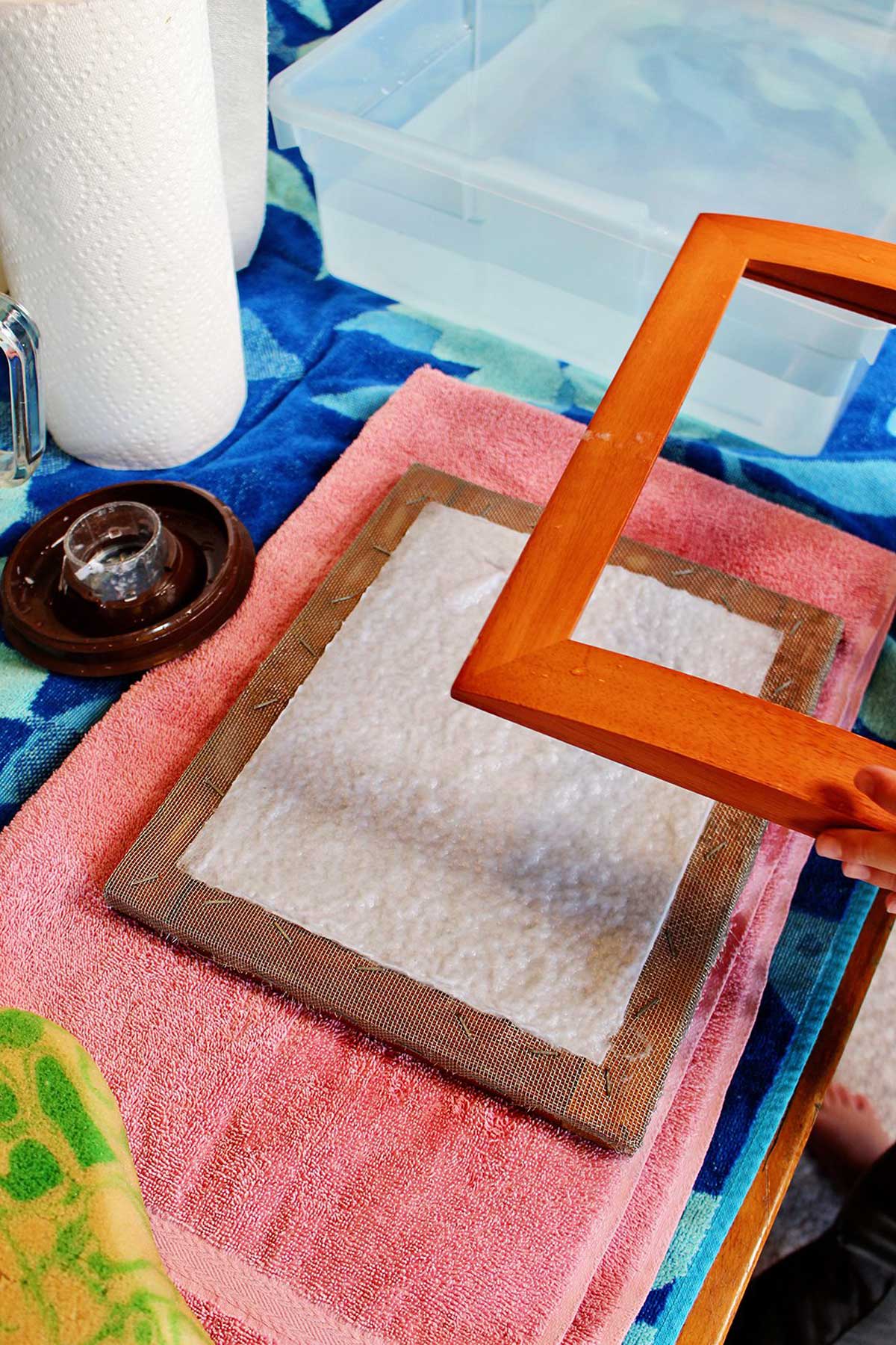 removing the mould from a mould and deckle with newly made recycled paper.