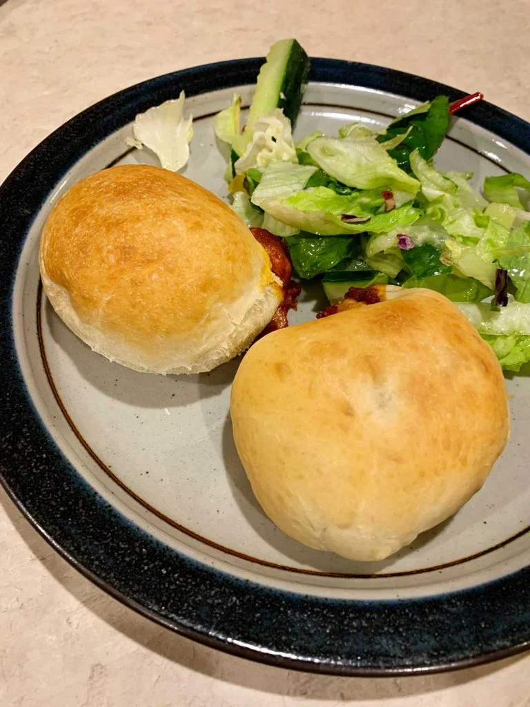 Homemade pizza pockets on a dinner plate alongside a salad.