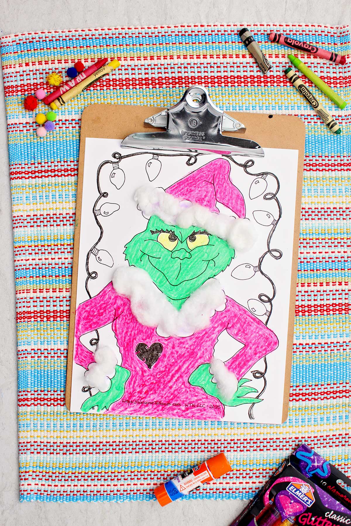 Completed Grinch colored printable enhanced with cotton ball accents attached to a clipboard.
